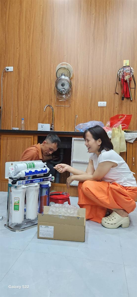 Hồng Nhung ngồi lắp máy lọc nước RO cùng thợ tại nhà khách