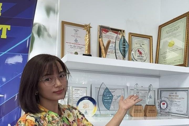 Hồng Nhung bên tủ giấy chứng nhận tại showroom