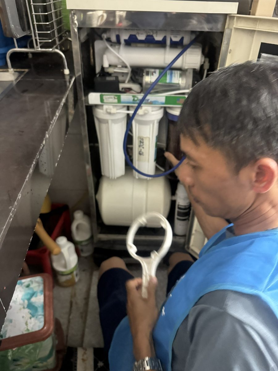 Anh kỹ thuật thay lõi máy lọc nước dưới bồn rửa nhà khách
